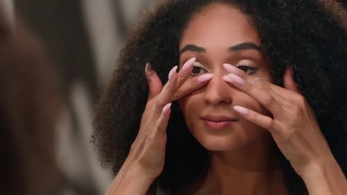 Woman Applying Cream to Face in Close Up