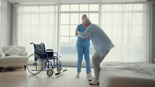 Nurse Helps Old Wheelchair Man to Stand Up Physical Therapist Woman Provides Medical Help Support to