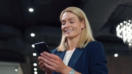 Caucasian Woman in Business Suit Typing Message on Modern Smartphone at Office