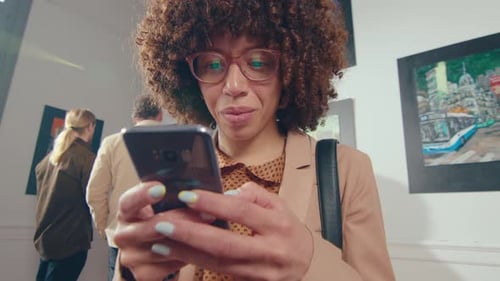 Female Visitor Texting on Phone in Art Gallery