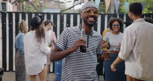 Portrait of Handsome Young African American Man Dancing and Drinking From Bottle Enjoying Street