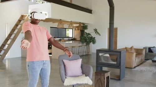 Using VR headset, man enjoying virtual reality experience in modern living room, copy space