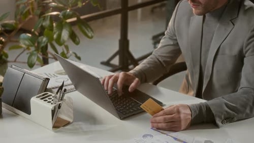 Midsection of Businessman Holding Bank Card Making Online Payment on Laptop