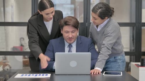 Three Colleagues Collaborating Around a Laptop in Office