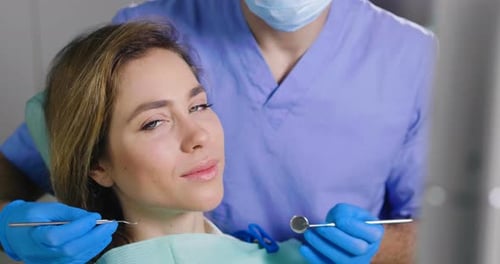 Dentist Examining Woman's Teeth in Clinic