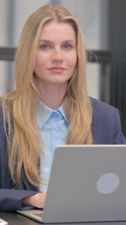 Smiling Woman Working on Laptop in Office Setting