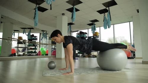 A Woman Performs a Challenging and Dynamic Exercise on a Stability Ball in the Gym