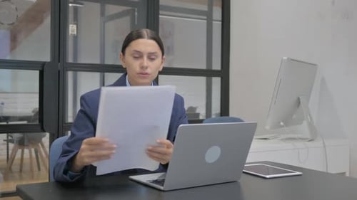 Business Woman Analyzing Documents at Office Desk