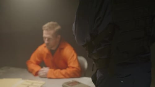 Police Officer Interrogates Prisoner in Dark Room