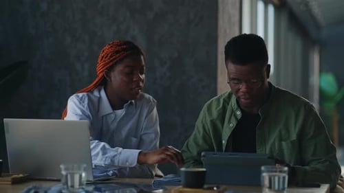 An AfricanAmerican Man and Woman are Engaged in Business Communication While in a Cafe with Coffee