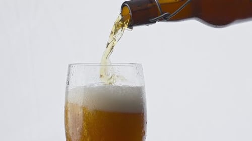 Closeup Dark Bottle Pouring Amber Tasty Beer Into Transparent Glass at White