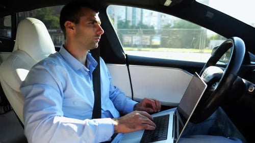 Handsome Entrepreneur Working on Notebook While Riding an Autonomous Self Driving Electric Car at