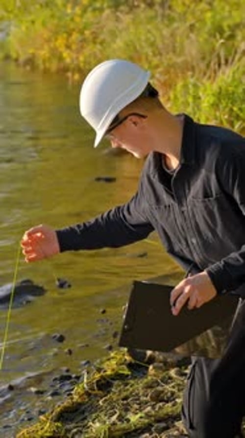 Young Man in Hardhat Tests River Water Quality