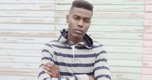 Portrait of african american man crossing arms and smiling in front of painted boards, slow motion