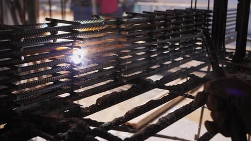 Welder Works at a Construction Site Sparks and Smoke Fly