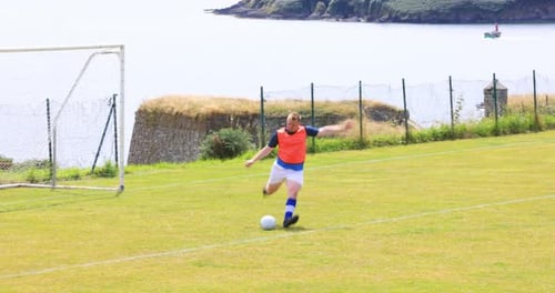 Man Kicks Soccer Ball near Coastal Field