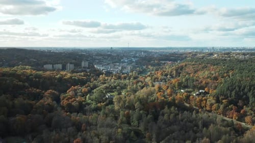 AERIAL: Vilnius city panorama with tranquil forest in autumn on a sunny day