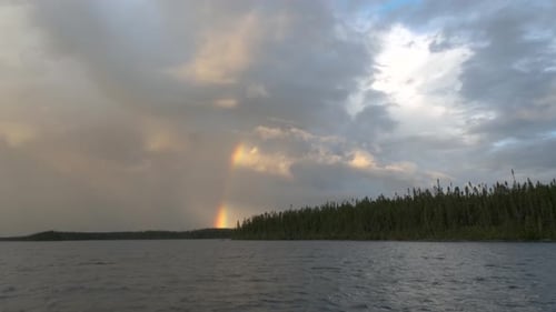 Magnificent sky over a lake with a rainbow piercing through the clouds