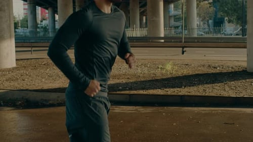 Close Up Shot of a Tired Athletic Muscular Young Man in Sports Outfit Jogging in the Street. He is