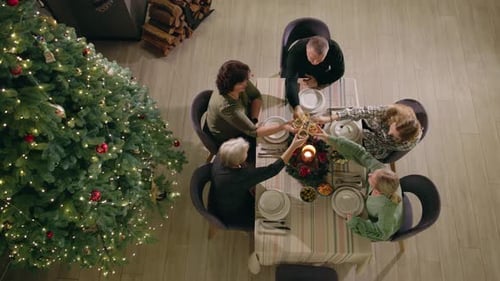 Family Gathering Around Table Next to Christmas Tree