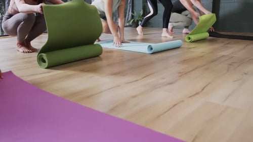 Women Unrolling Yoga Mats on Studio Floor