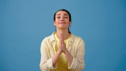 Woman Praying in Hopeful Anticipation against Blue Background