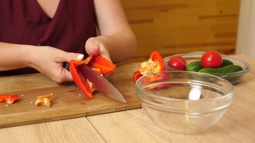 Woman Cuts Red Bell Pepper in Kitchen for Cooking
