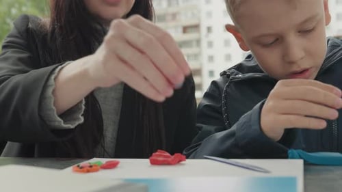 Woman and Boy Create Clay Figures at Table