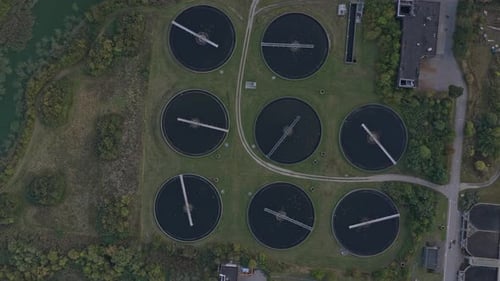 Aerial video still of Denmark wastewater facility, clarifiers and pipes.
