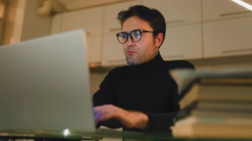 Man Uses Laptop at Table Indoors
