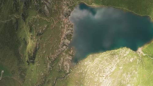 Aerial overhead reveal shot of mountain lake Lago Grande on a sunny day. Camera is moving from left