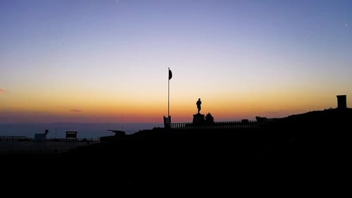 Monument and Flag Stand on Hill at Sunrise