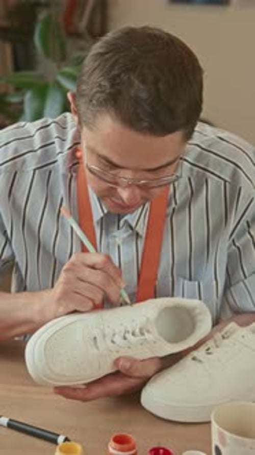 Young Adult Customizing White Shoe with Pencil