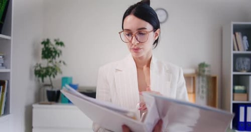 Businesswoman Analyzes Financial Report in Binder