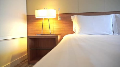 Empty holiday hotel room and candid double bed with white linen. Panning