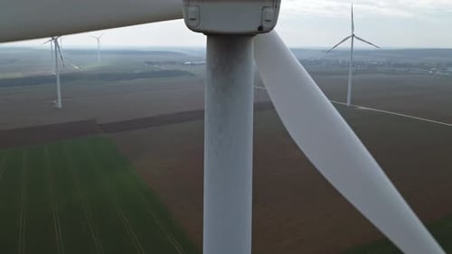 Rising with a drone behind a wind turbine, at the background with other wind turbines.