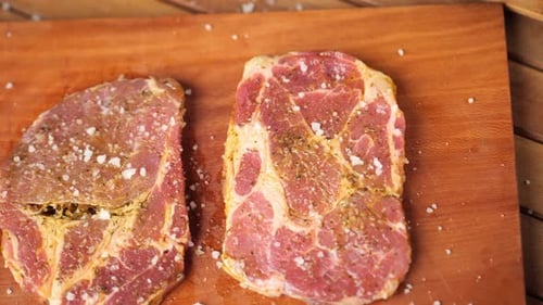 Topdown shot of 2 steaks lying on a wooden board on a table close up