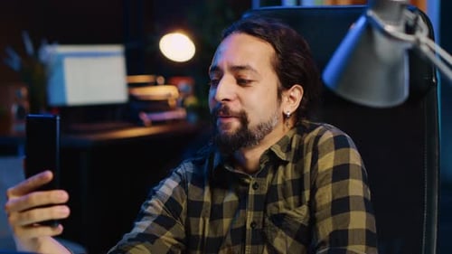 Young Adult Video Chats on Phone at Desk