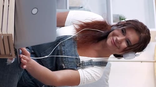 Woman with Headphones Uses Laptop at Home