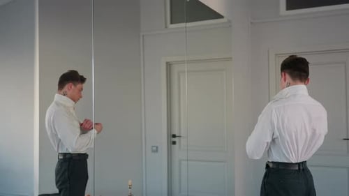 Rear View Man Buttoning White Shirt and Adjusting Belt By Loft Studio Mirror