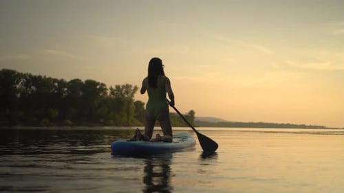A Beautiful Silhouette of a Person Paddleboarding During a Serene Sunset By the Lake