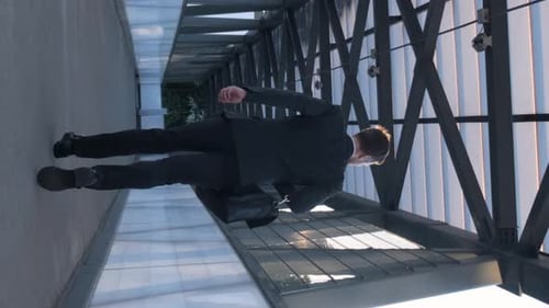 Ein Geschäftsmann mit einer Aktentasche rennt schnell ins Büro, Rückansicht, Vertikal