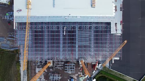 Descending Drone Shot of Large Steel Building Roof Being Built at Construction Site, Aerial View