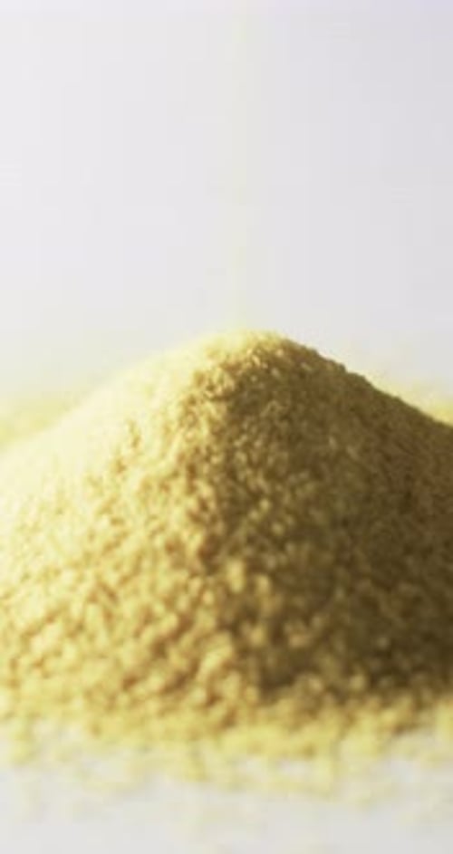 Vertical video of close up of heap of yellow sand grains and copy space on white background