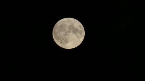 Full harvest moon crater surface closeup passing across dark night sky