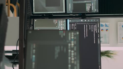 Vertikale Videocomputerbildschirme auf dem Schreibtisch im leeren Datenraum mit Anzeige von Programmcode und