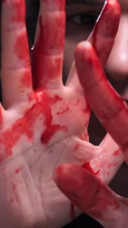 Hand Covered in Fake Blood Against Dark Background