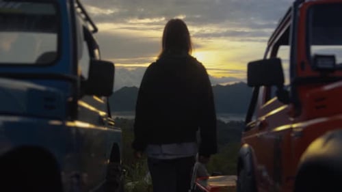 Woman Enjoying Mountain Sunrise with Off-Road Vehicles