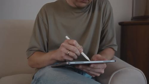 Man Using Stylus Pen on Tablet Device Indoors