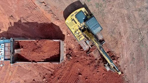 On Construction Site Excavator Loads Earth Into Machine Thereby Preparing Area for Construction